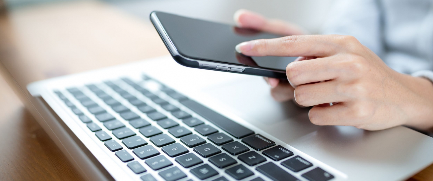 Woman,Hand,Using,Mobile,Phone,And,Laptop,Computer